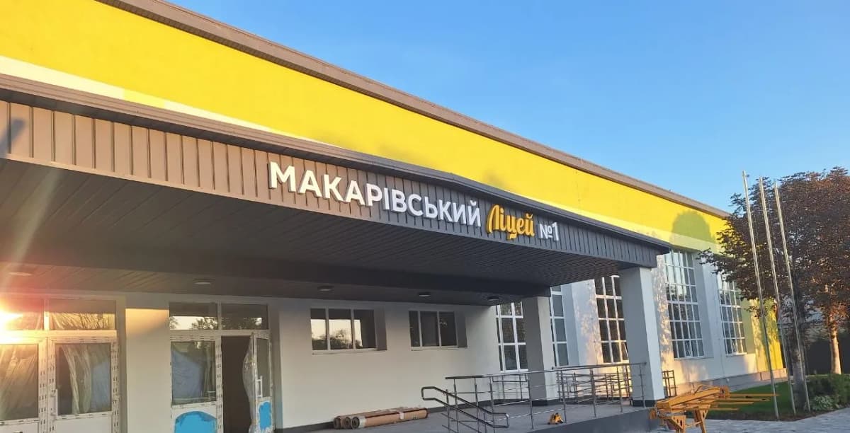 Вивіска «МАКАРІВСЬКИЙ Ліцей №1»: білі й жовті об’ємні літери на темному похилому козирку над входом до ліцею